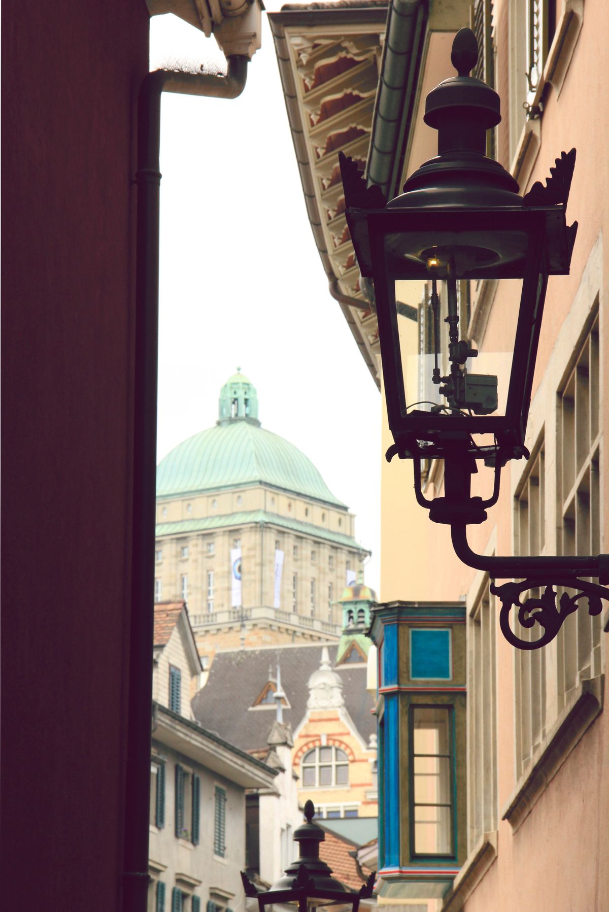 This shot was taken in on of the many narrow alleys in Zurich City. I tried to capture urban furnitre- a lamp in the foreground and University of Zurich in the background